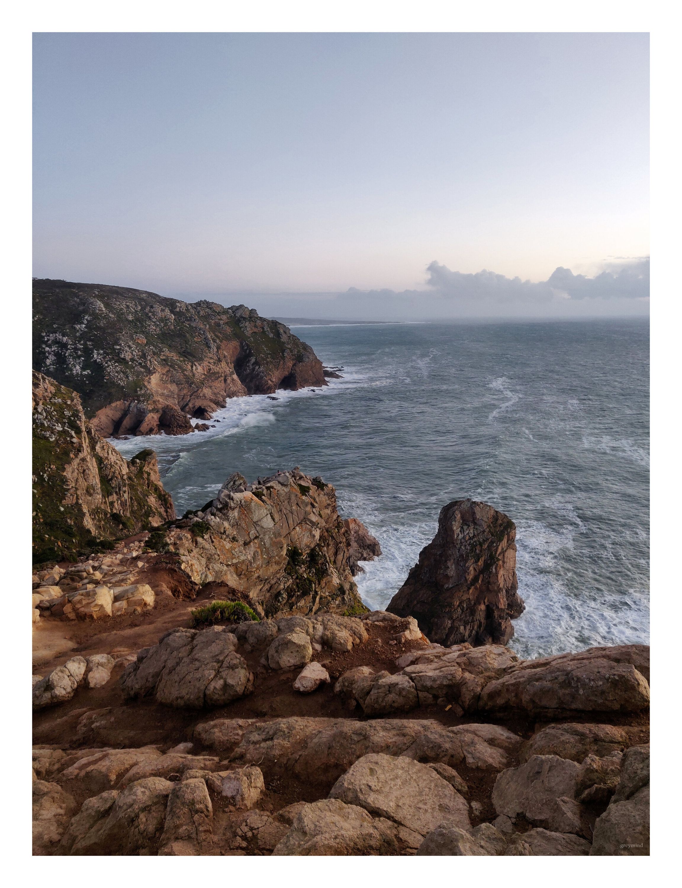 Rugged rocks and cliffs above a churning Atlantic at dusk.