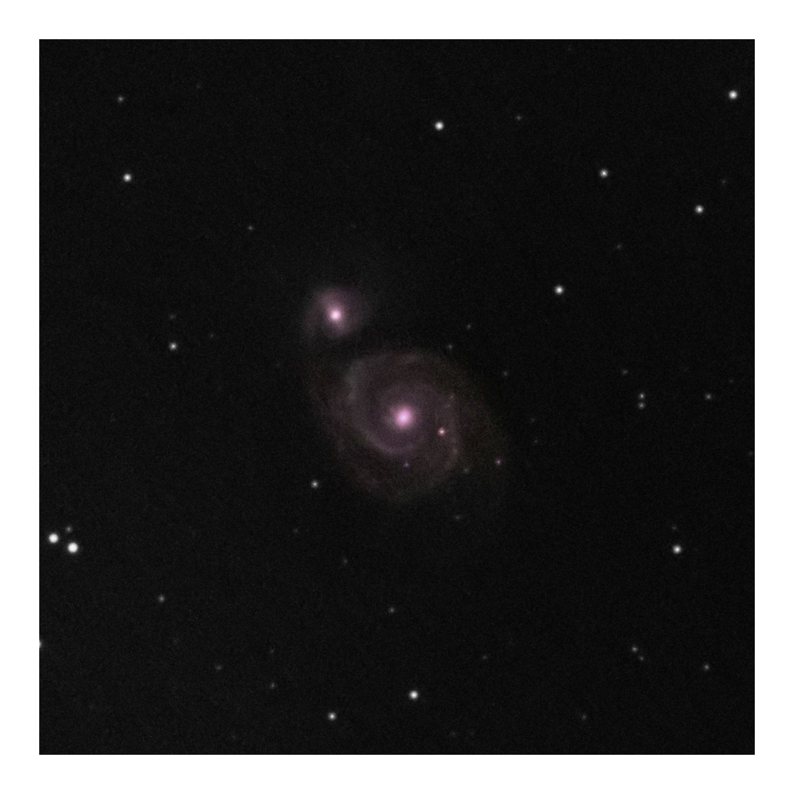 The Whirlpool Galaxy, a faint purple spiral beside its small companion, among scattered stars on black.